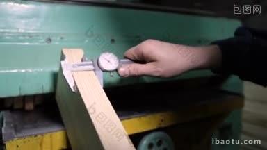 木匠在木工店用卡尺测量木槽的特写过程中用卡尺测量木板的厚度